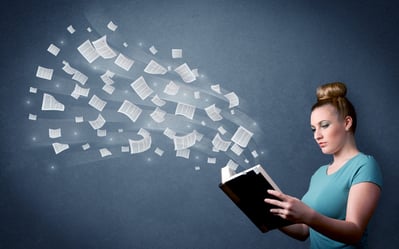 Casual young woman holding book with pages flying out of it